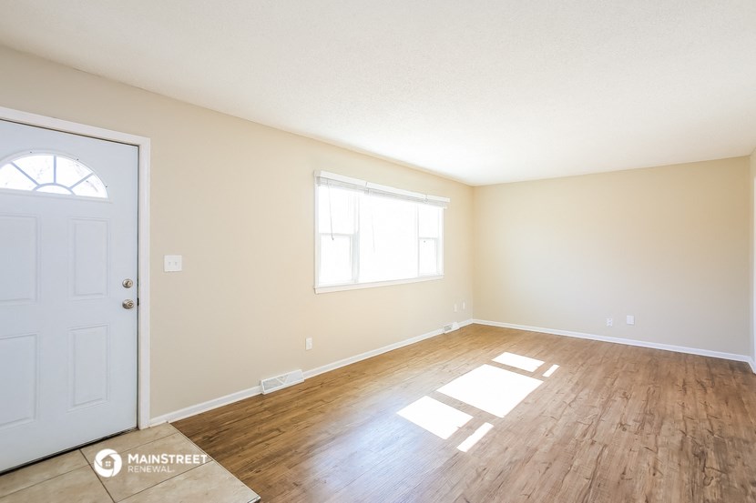 the spacious living room with wood flooring and a white door