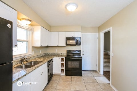 a kitchen with white cabinets and black appliances and a granite counter top