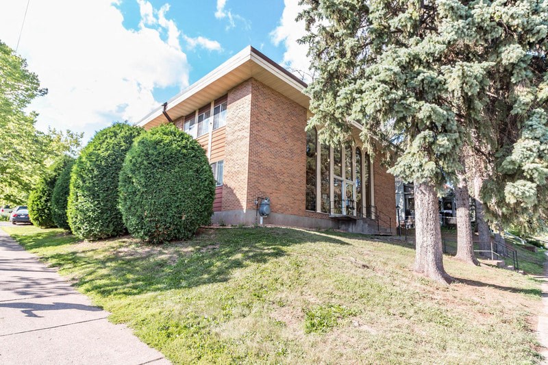 the front of a brick building with trees and grass