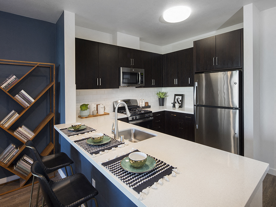 A kitchen with a white counter top and black cabinets.