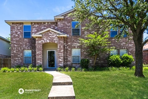 front view of a brick house with trees and grass