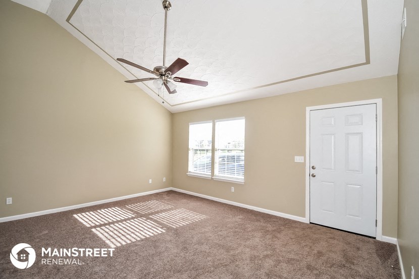a living room with a ceiling fan and a white door