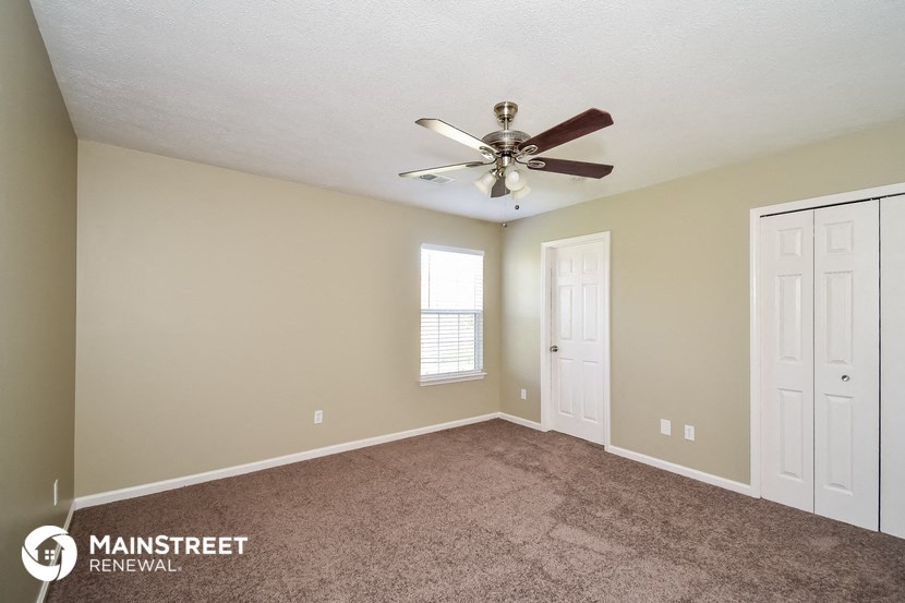 the master bedroom has a carpeted floor and a ceiling fan