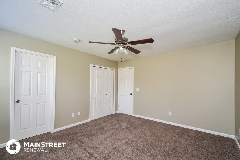 the spacious living room with carpeting and a ceiling fan