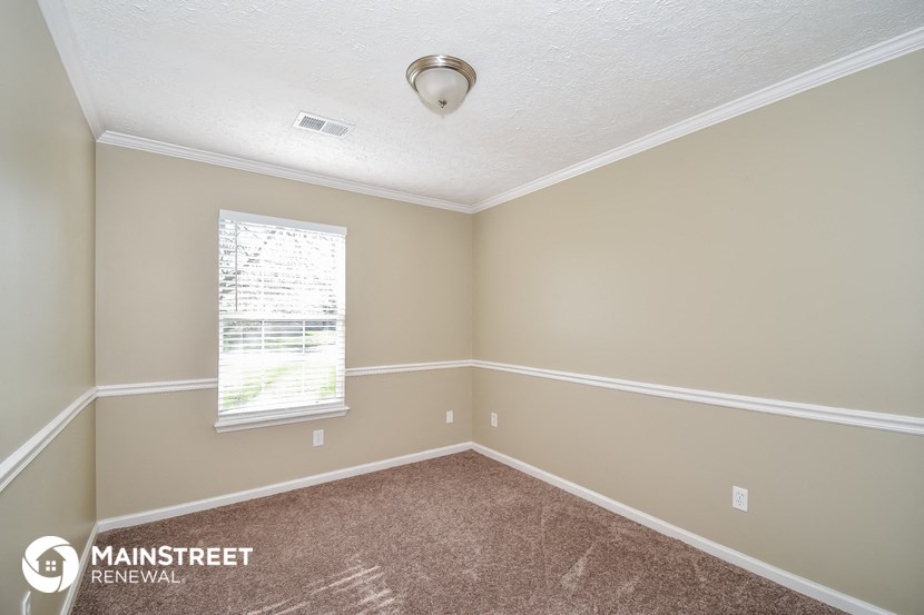 the bedroom of a rental home with carpet and a window