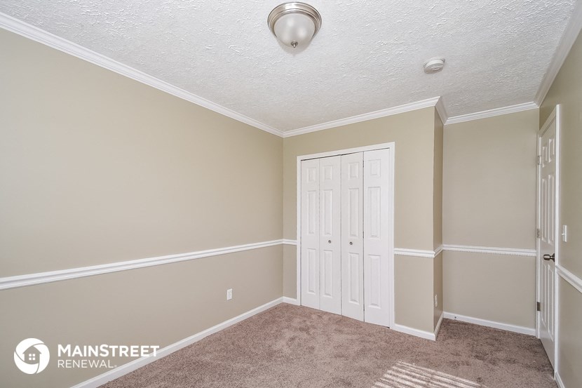 a bedroom with white doors and carpet and a door to a closet