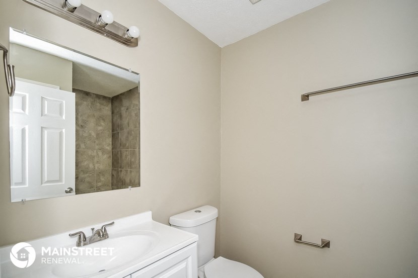 a white bathroom with a white sink and toilet and a mirror
