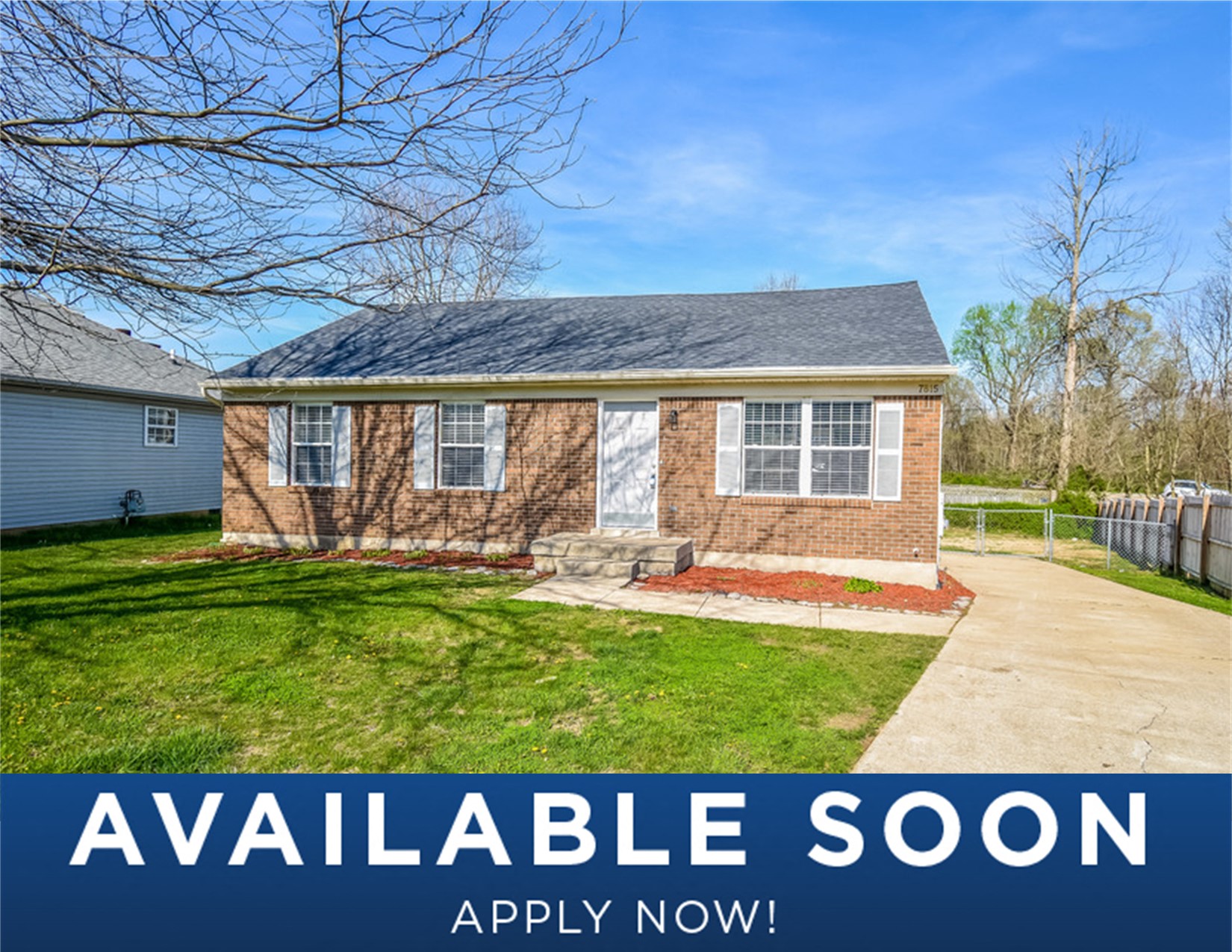 a small brick house with a green lawn and a driveway