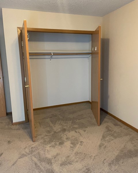 an empty bedroom with a closet with a door open