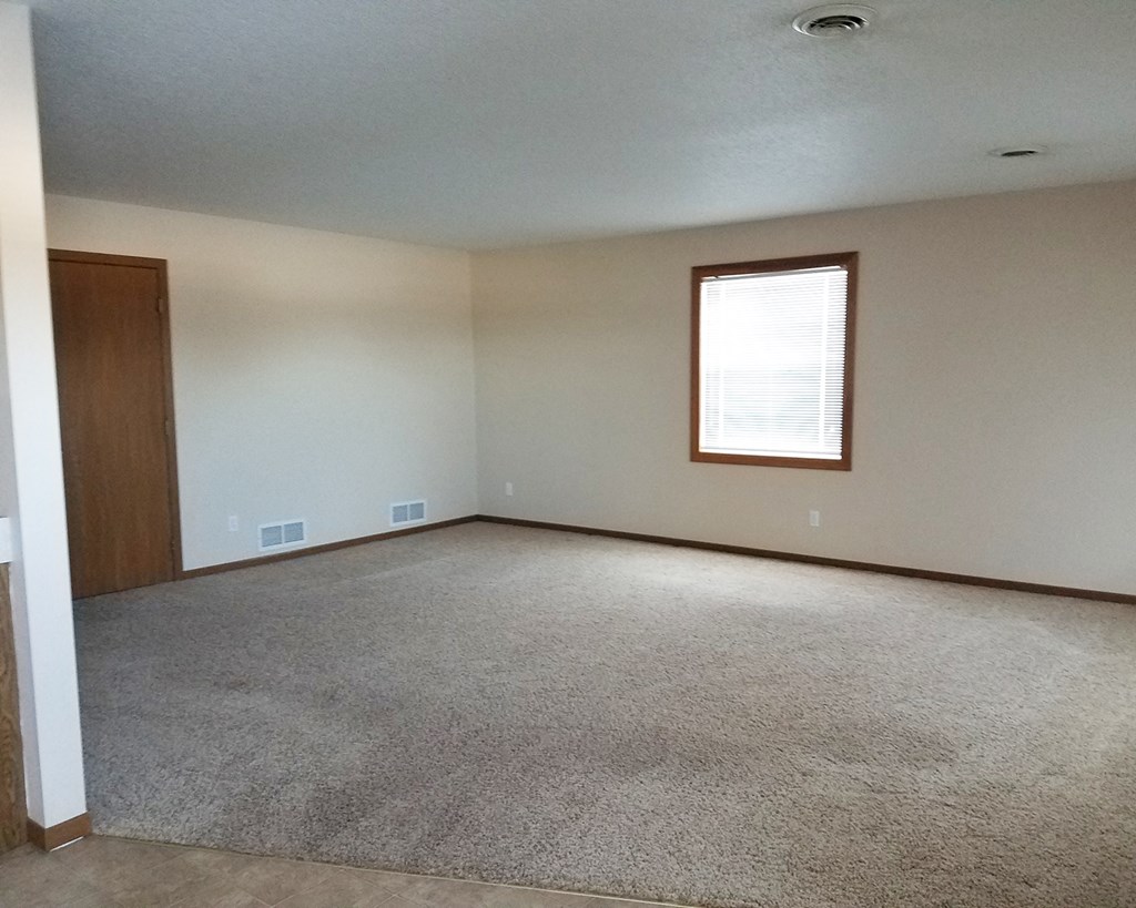 an empty living room with white walls and a window