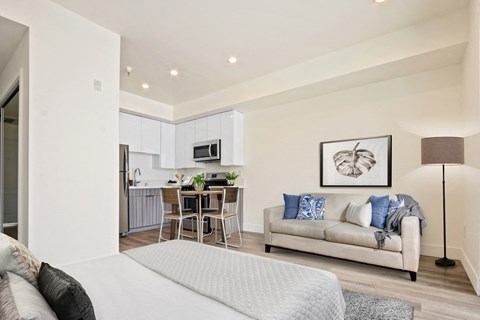 A modern living room with a grey sofa and a dining table set in the background.