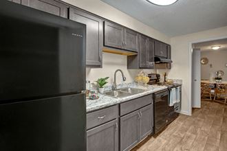 Kitchen, wood-like flooring, granite countertops, black appliances, extended sink