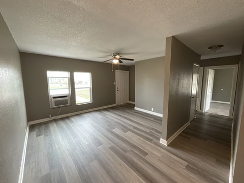 A room with a ceiling fan and a window overlooking a parking lot.