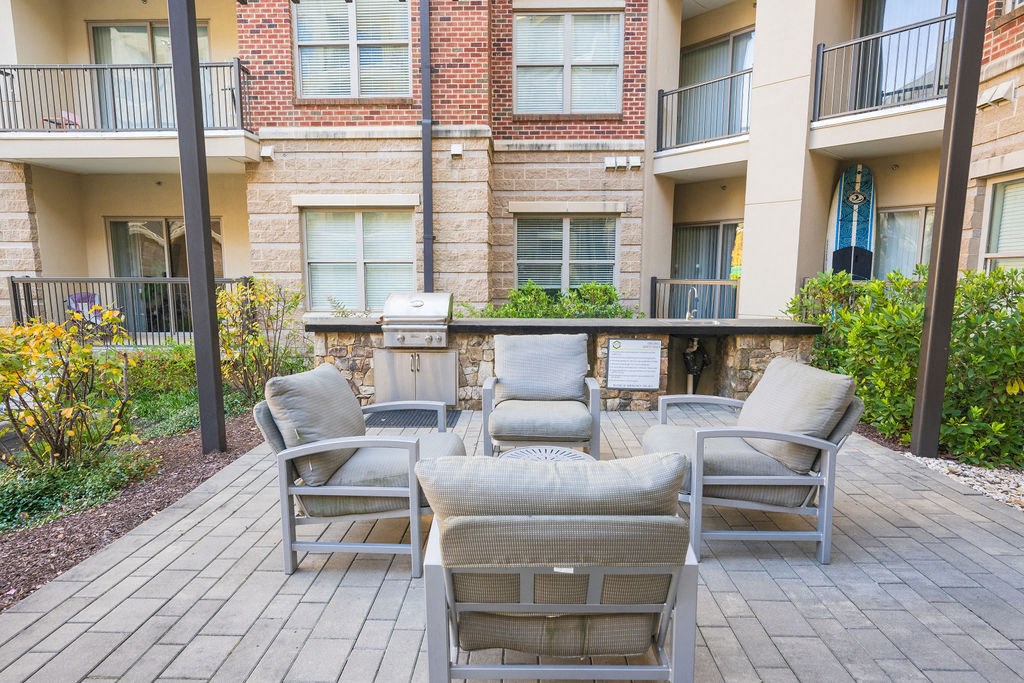 a patio with chairs and a table in front of an apartment building