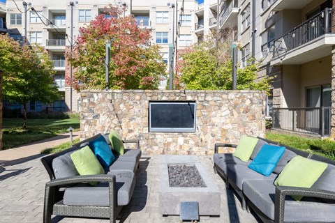a lounge area with couches and a fireplace in front of an apartment building