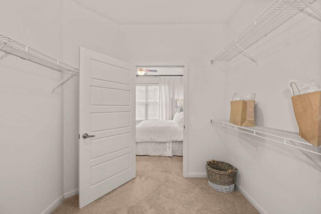 a closet with a white door and a bedroom in the background