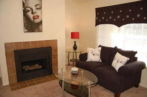 A living room with a fireplace, a couch, a table, and a painting on the wall.
