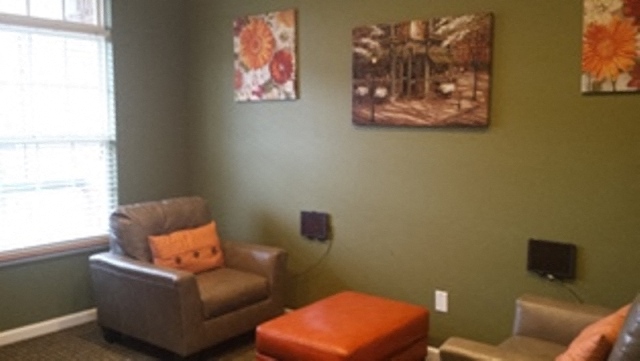 a living room with a chair and an orange pillow