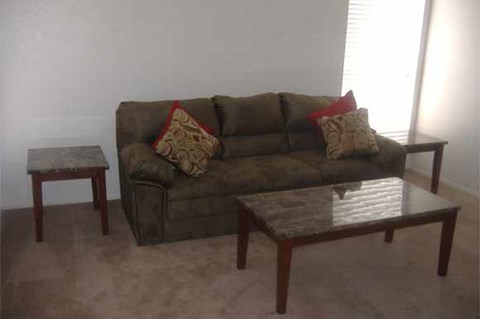 A brown couch with two pillows and a small table in front of it.