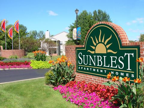 a sign that says sunless apartment homes with flowers in front of it