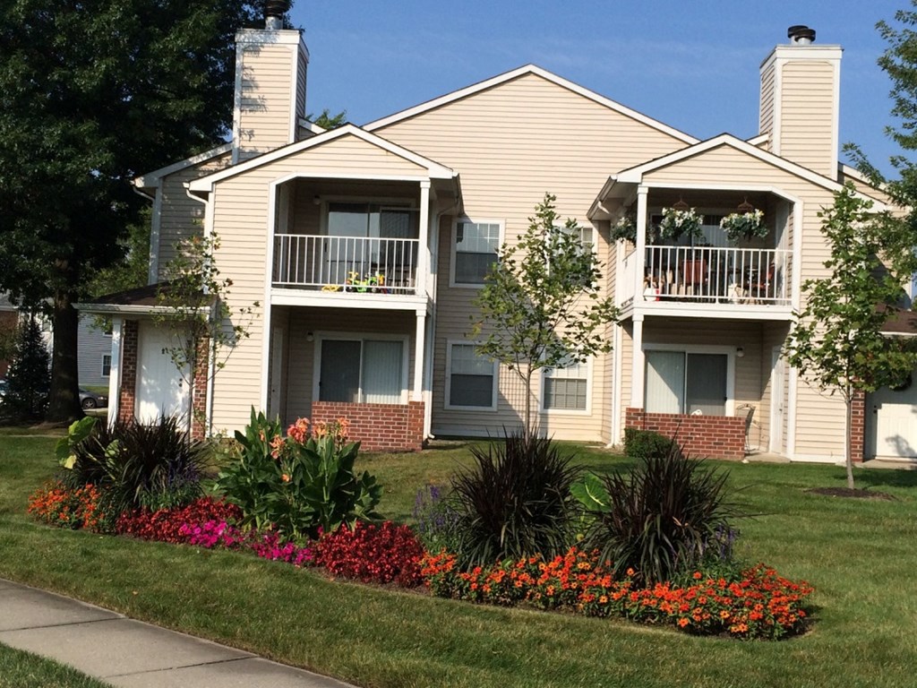 the view of an apartment building with flowers in the yard