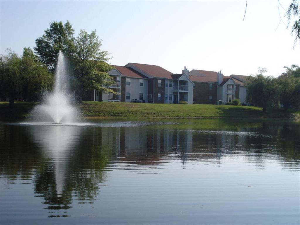 a fountain in the middle of a lake with apartments in the background