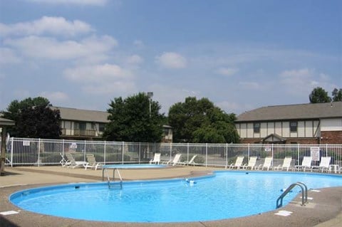 a swimming pool with white chairs and a fence around it