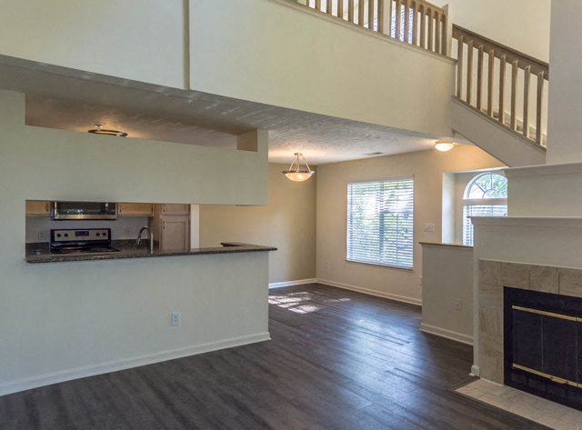 an empty living room with a fireplace and a kitchen