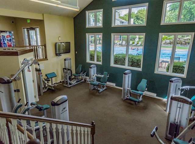 a fitness room with weights and chairs and windows