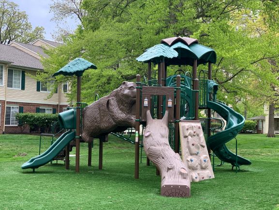 a playground with a bear playing on a slide