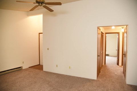 a living room with a ceiling fan and a carpet