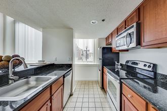 a kitchen with black granite countertops and white tile flooring