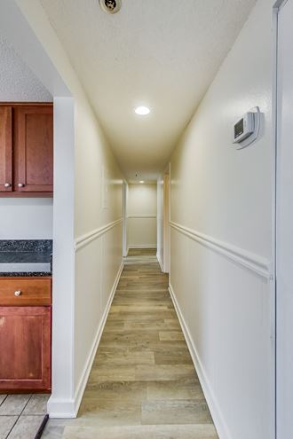 a corridor with white walls and wood floors