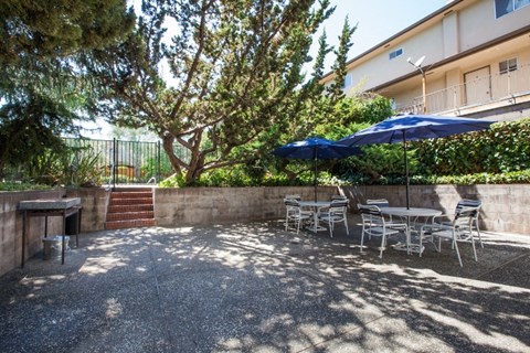 a patio with a table and chairs and umbrellas