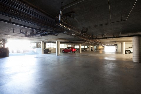 a large parking garage with a red car in the distance