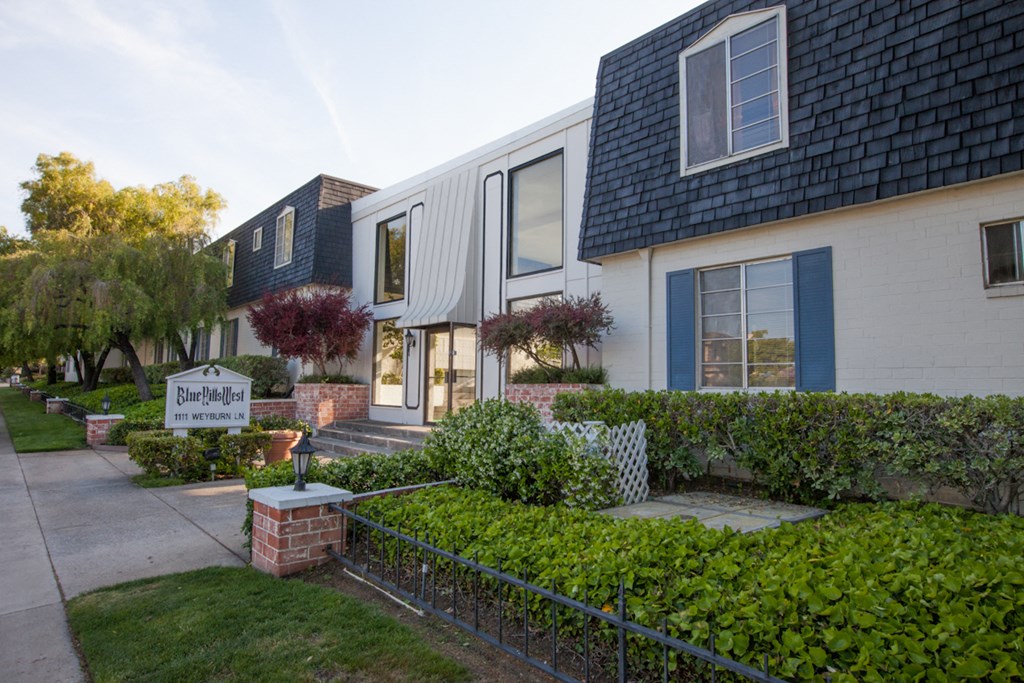 a white house with a sidewalk and a sign in front of it