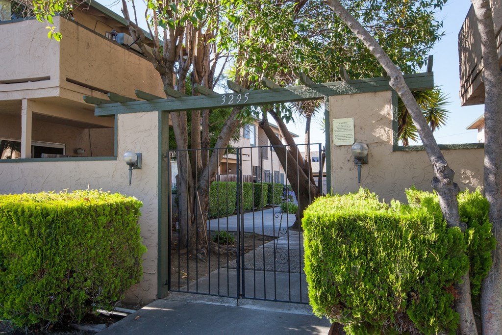 the gate to the entrance of a building with a fence and trees