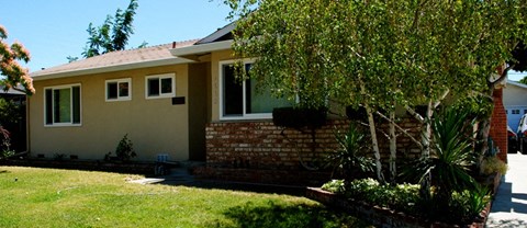 A house with a yellow siding and a red brick chimney.