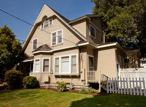 a yellow house with a white fence in front of it