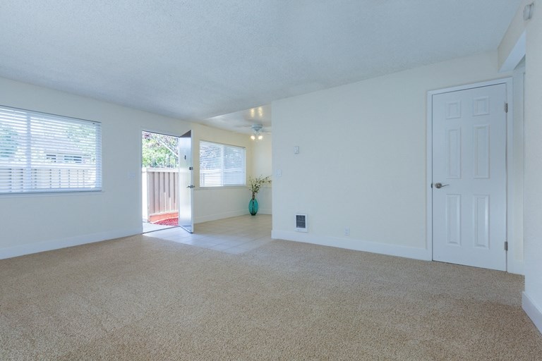 a spacious living room with white walls and carpet