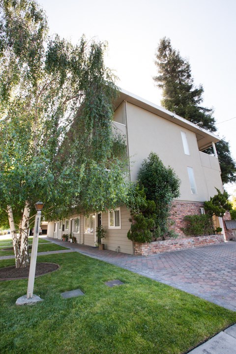 the side of a house with a yard and a sidewalk