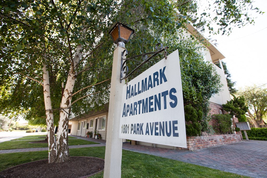 a sign for hillmark apartments in front of a tree