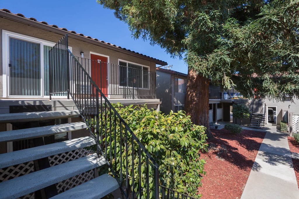 a building with a red door and a staircase with a bench in front of it