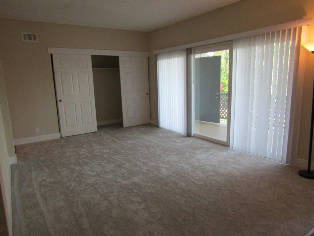 an empty living room with sliding glass doors to a patio