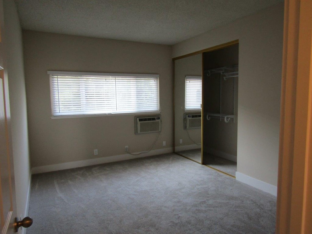an empty room with a window and a closet