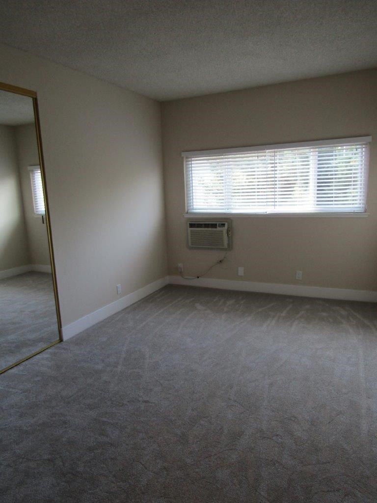 an empty living room with a window and carpet