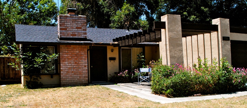 A house with a brick chimney and a covered patio.