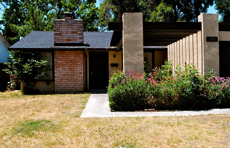 A house with a brick chimney and a stone pillar.
