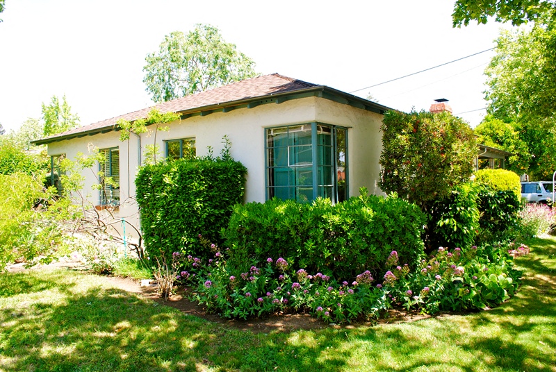 A white house with a green door and a garden in front.