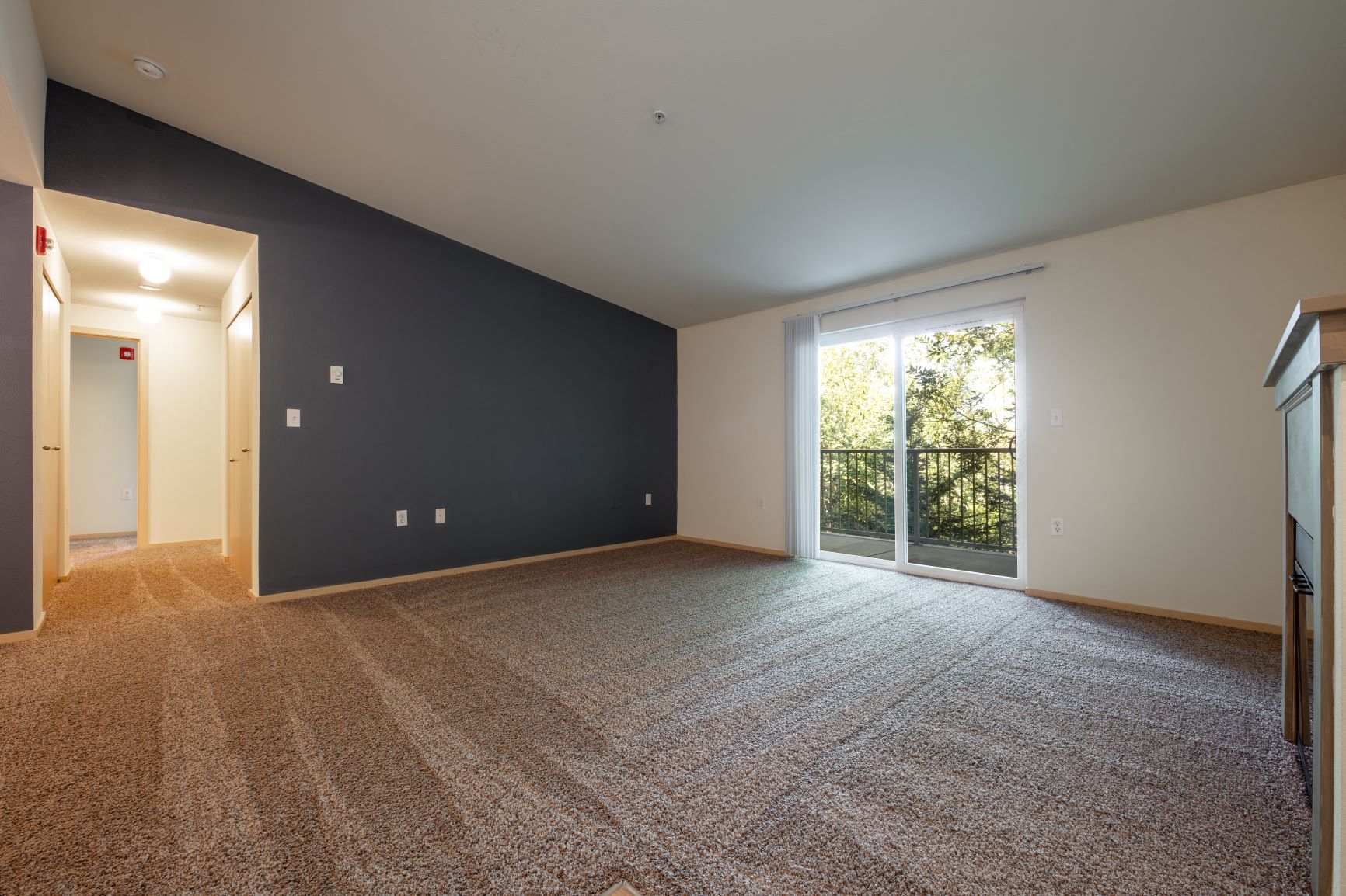 a living room with a large window and a carpeted floor